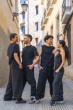 Four diverse young friends wearing black casual clothing are happily interacting, smiling, and