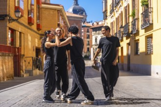 Group of young adult dancers rehearsing a modern dance performance on a cobbled street in a