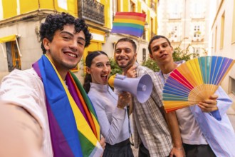 Group of diverse young people smiling and celebrating gay pride movement while holding a rainbow
