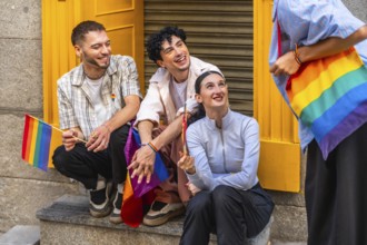 Group of diverse friends expressing joy and belonging, holding rainbow flags and carrying a rainbow