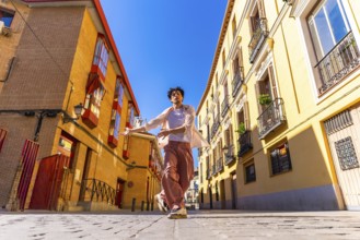 Young man freely dancing in a cobblestone street between traditional architecture buildings under a