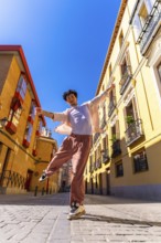 Young man actively posing and dancing on a cobblestone city street in historic european