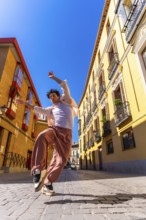 Man dancing energetically on a sunny cobblestone street in madrid, showcasing urban style and
