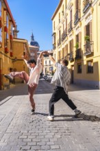Two energetic young men performing a street dance on a cobblestone street in a lively european