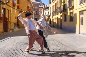 Two young men performing energetic contemporary street dance on cobblestones in madrid, expressing