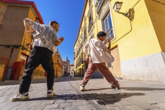 Two young men expressing themselves through street dance movement, performing a modern hip hop