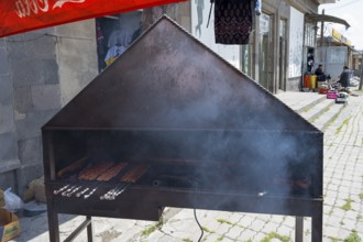 Outdoor barbecue with meat skewers, smoke rising, on a metal rack, minced meat on a spit, Martuni,