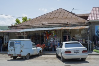 A rustic shop with cars in front of it, in a rural street scene, Martuni, Gegharkunik province,
