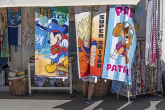 Tourists in a souvenir shop, bath towels with various comic motifs, in Vila Real de Santo António,