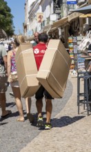 DPD courier, carrying parcels in the historic centre of Lagos, Algarve, Portugal, delivery on foot,
