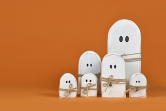 Cute wooden white Halloween ghost ornaments on orange background