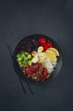 Fresh poke bowl with tuna, avocado, and vegetables served on a black plate
