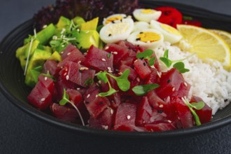 Fresh poke bowl with tuna, avocado, and vegetables served on a black plate