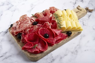 Assorted meat, appetizer, prosciutto, salami and ham, with maasdam cheese and olives, on a wooden