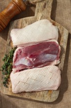 Fresh raw duck breast, on a wooden chopping board, top view, no people