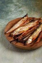 Cold smoked capelin, on a wooden bowl, top view, no people