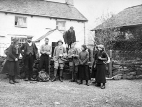 Men and women in mountaineering mountain climbing group standing in fron of cottage, c 1900-1920