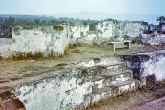 British expatriate tourist woman sitting on bench by walls ruin thought to be Malacca or Melaka,