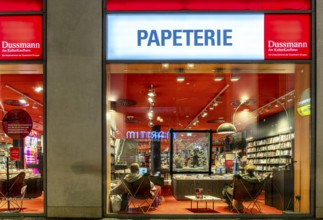Dussmann GmbH, Bookstore, Urban scene in the evening with reflections in the window pane and a view