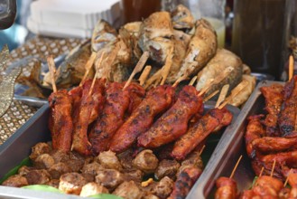 Grilled red marinated Thai chicken meat skewers at street food market