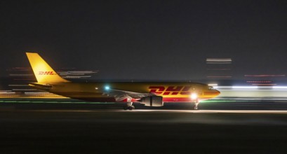 Stuttgart Airport in the early morning. DHL cargo plane landing. Light traces with motion blur.