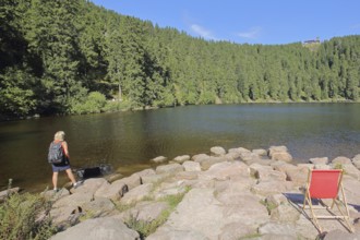 Lake landscape and empty deckchairs with tourist on the lakeshore, mountain, forest, Karsee,