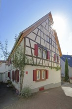Half-timbered house with red shutters against the light, Höllgasse, Wiesloch, Baden-Württemberg,