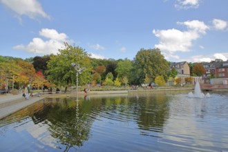 Bastinsweiher with sculpture, seating, bench, people, pedestrians, park, pond, autumn colours,