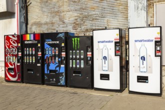 Row of popular bottled cold soft drinks and mineral water brands for sell in vending machines on