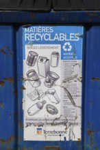 Close-up of accepted recyclable materials list on blue metal with black plastic lid industrial size