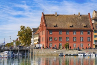 Historic building with red façade on the waterfront next to a harbour, Meersburg, Lake Constance,