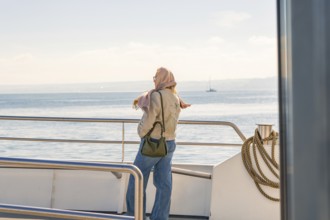 Woman on boat looking at the sea, wearing scarf, relaxed atmosphere, Meersburg, Lake Constance,