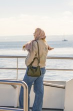 Woman looking at the sea from the boat, wearing scarf and jeans, relaxed mood, Meersburg, Lake