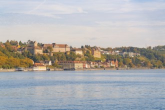 Town view on the lakeshore with historic buildings and autumnal trees under a blue sky, Meersburg,