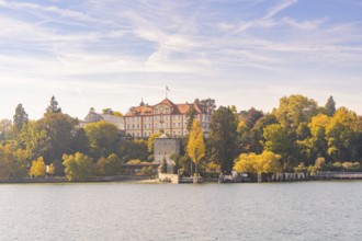 Castle surrounded by autumn trees on the lake under a blue sky, Mainau Island, Lake Constance,
