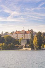 Historic castle with tower on the lakeshore surrounded by autumn trees, Mainau Island, Lake