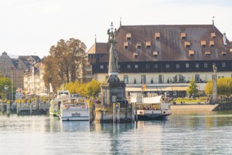 Harbour with a statue, several buildings and adjacent ships on a calm water, Constance, Lake