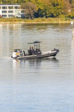 People in a police motorboat gliding across the calm lake on a sunny day, Constance, Lake