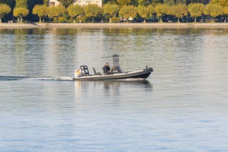 Police motorboat with two people travelling over calm water near the shore, Constance, Lake