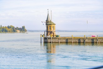 A picturesque harbour with a lighthouse, quietly situated on a clear water with houses in the