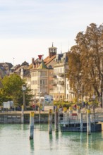 City view with historic buildings, clock tower and modern harbour area on a calm water, Constance,