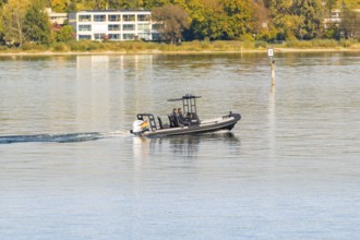 Fast police motorboat with two passengers travelling across the calm waters of a lake, Constance,