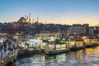 Restaurant boats on the shore of Eminönü, Rüstem Pasha Mosque and Suleymaniye Mosque at dusk,