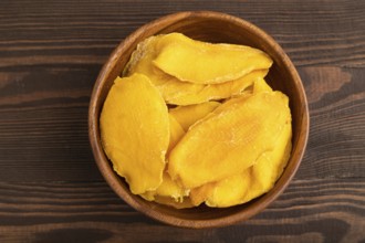 Dried Mango in wooden bowl on brown wooden background. Top view, close up, flat lay. healthy food,