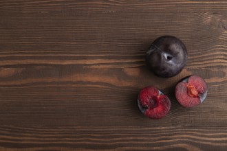Purple Plum Cut in half on brown wooden background. Top view, flat lay, copy space. healthy food,