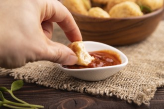 Fried crispy Chicken Nuggets with ketchup, microgreen on brown wooden background and linen textile