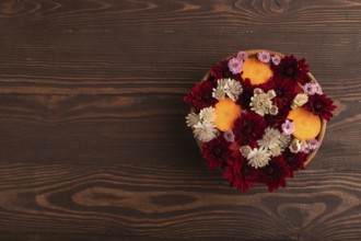 Wooden bowl with carrot slices and red Chrysanthemum flowers, Astrantia flowers, flower salad on