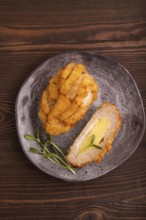 Chicken Schnitzel on gray plate with microgreen on brown wooden background. top view, flat lay,