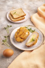 Chicken Schnitzel on blue plate with microgreen on brown concrete background and orange linen