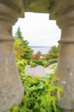 View through stone pillars of a landscape with trees and a large body of water, Mainau Island, Lake